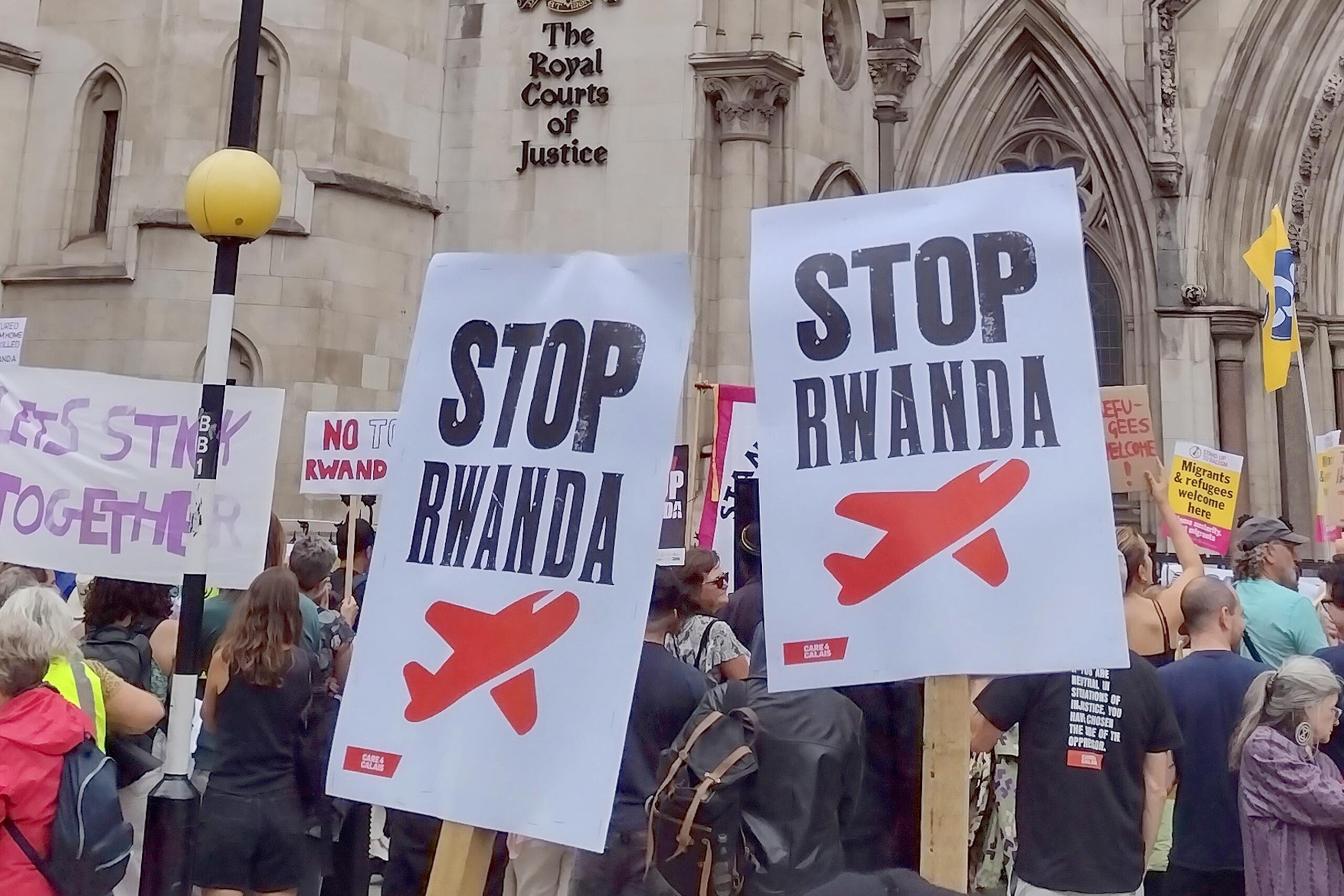 Demonstrators hold placards against the Rwanda plan, at a protest outside the Royal Courts of Justice in London.