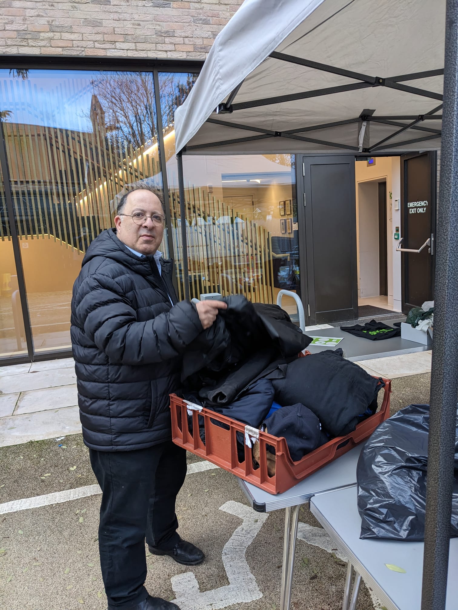 HIAS+JCORE's Executive Director David Mason stands holding a box containing donated clothes.