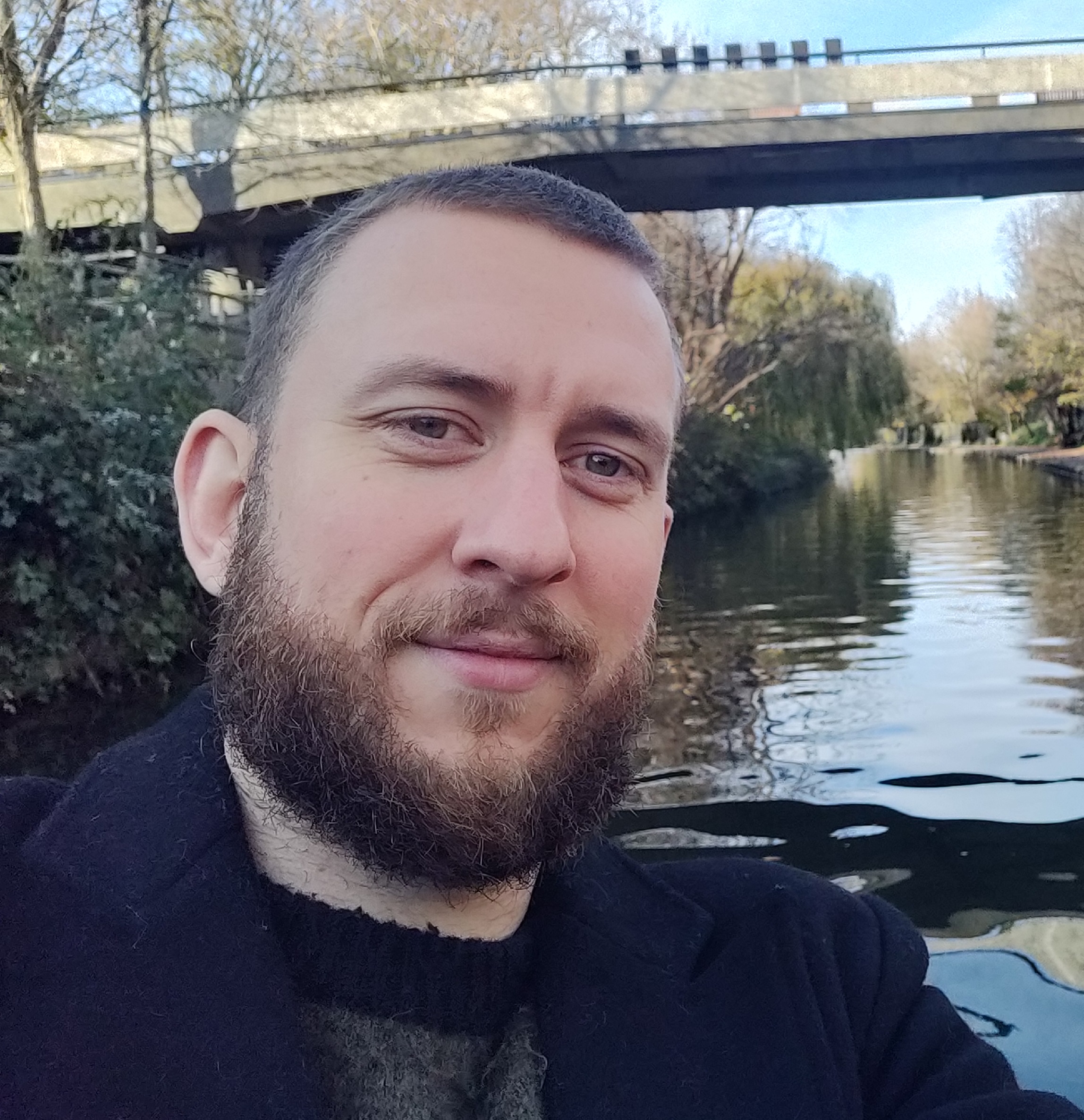 Selfie of Eric Schloss. Eric is smiling at the camera, stood in front of a river.