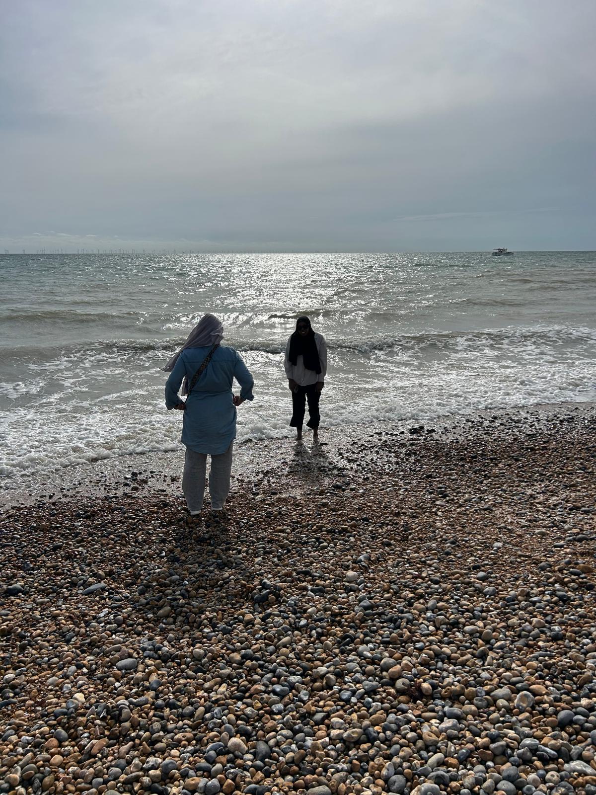 Two young female JUMP participants are stood by the sea at Brighton.